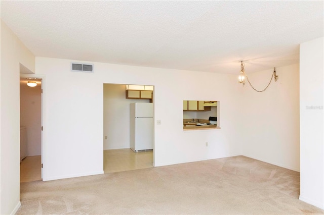 carpeted spare room featuring a chandelier and a textured ceiling