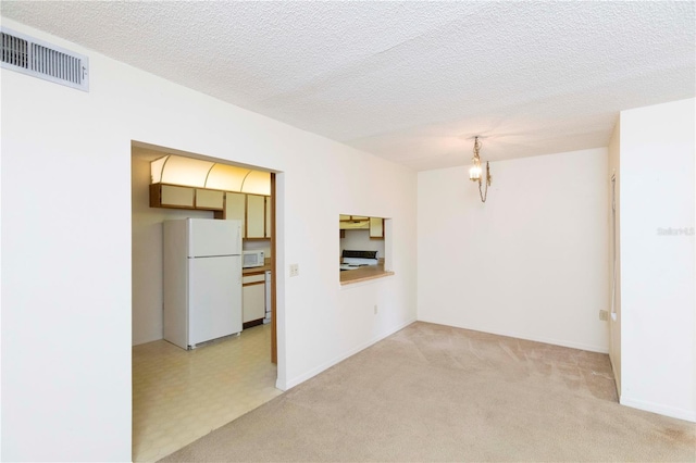 unfurnished room featuring a notable chandelier, light colored carpet, and a textured ceiling