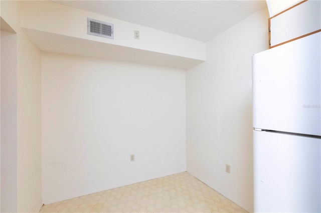 kitchen with white refrigerator and a textured ceiling