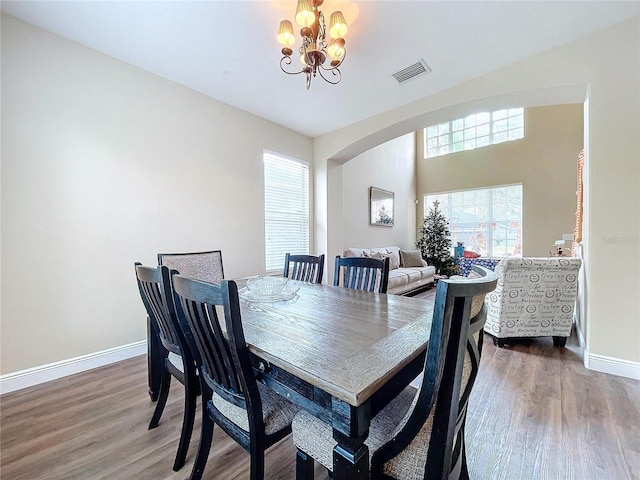 dining area with hardwood / wood-style floors and an inviting chandelier