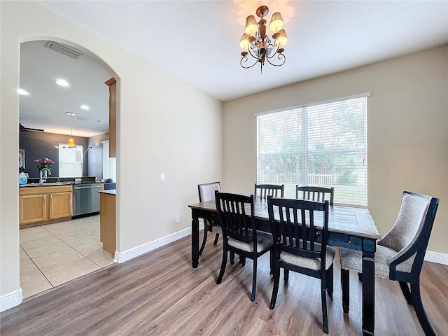 dining room with sink, light wood-type flooring, and an inviting chandelier