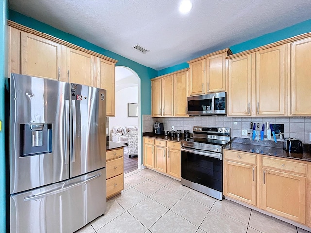 kitchen with decorative backsplash, light brown cabinetry, stainless steel appliances, and light tile patterned floors