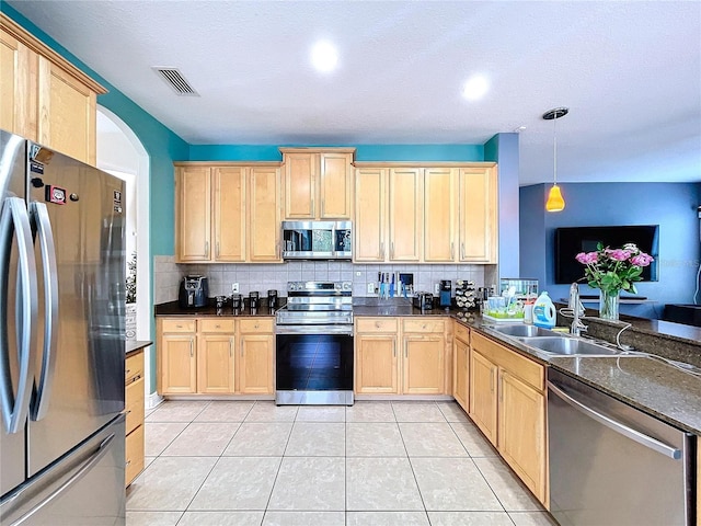 kitchen with appliances with stainless steel finishes, decorative light fixtures, light brown cabinetry, and sink