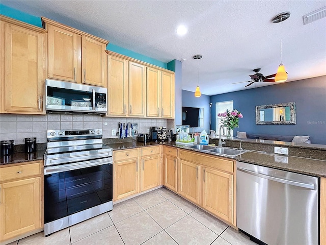 kitchen with pendant lighting, decorative backsplash, sink, and appliances with stainless steel finishes