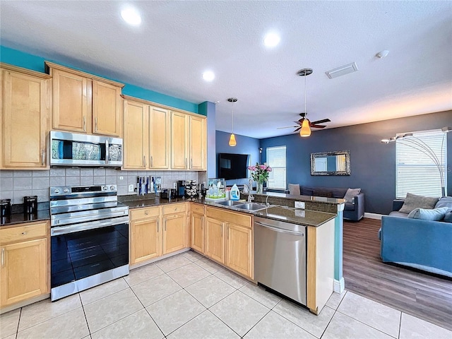 kitchen featuring ceiling fan, sink, kitchen peninsula, decorative light fixtures, and appliances with stainless steel finishes