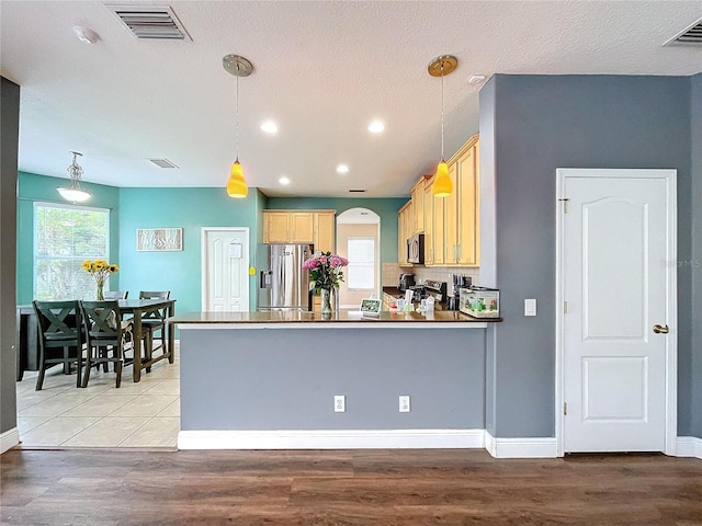 kitchen with appliances with stainless steel finishes, decorative light fixtures, and light brown cabinetry