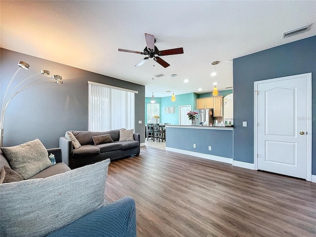 living room featuring ceiling fan, dark hardwood / wood-style flooring, and a textured ceiling