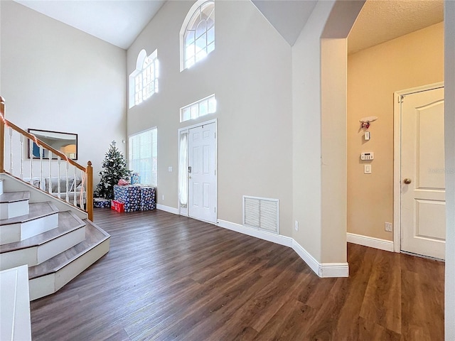 foyer featuring a towering ceiling and dark wood-type flooring