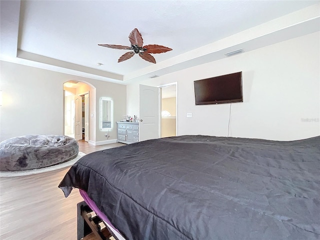 bedroom with a tray ceiling, light hardwood / wood-style flooring, and ceiling fan