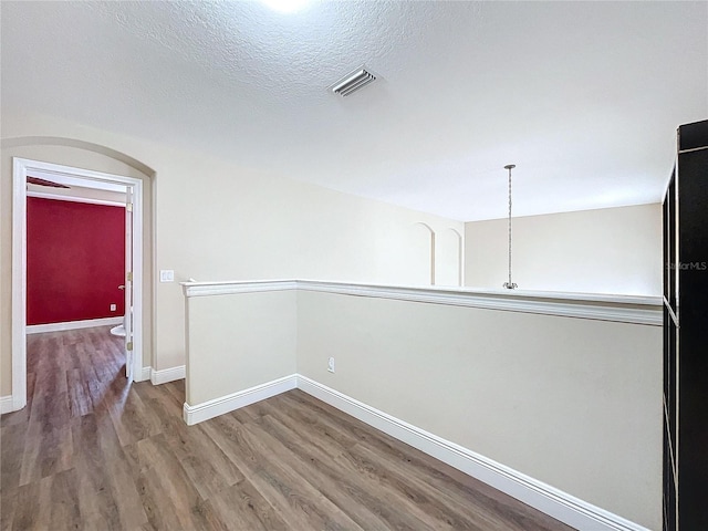 unfurnished room with a textured ceiling and hardwood / wood-style flooring