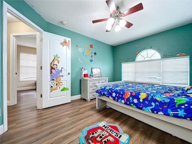 bedroom with ceiling fan, wood-type flooring, and multiple windows