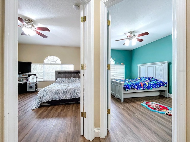 bedroom with ceiling fan, light wood-type flooring, and a textured ceiling