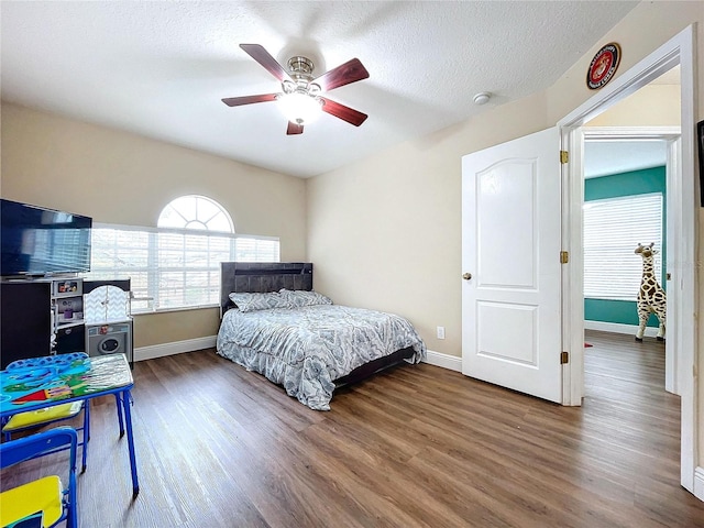 bedroom with ceiling fan, dark hardwood / wood-style flooring, and a textured ceiling