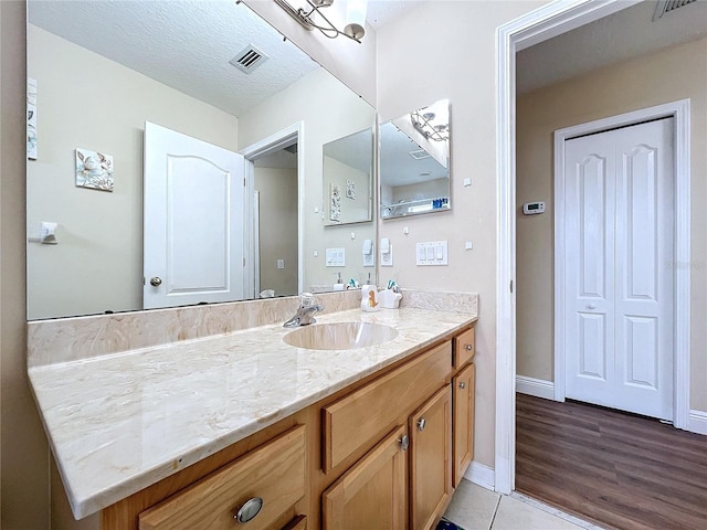 bathroom featuring tile patterned flooring, vanity, and a textured ceiling