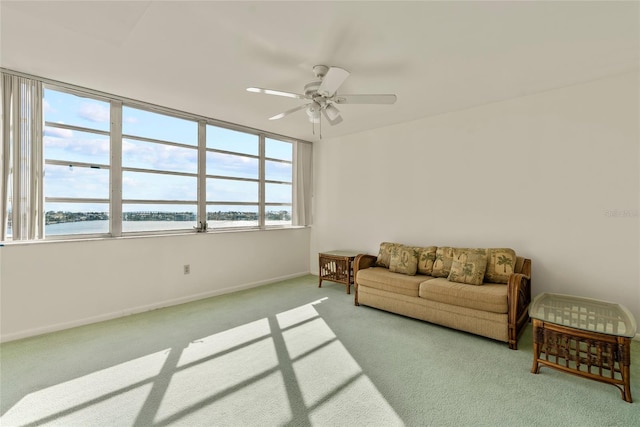 living room with ceiling fan, a water view, and light colored carpet