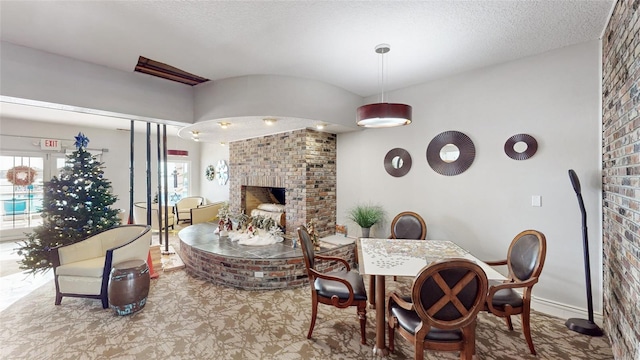 living room featuring a wealth of natural light, a textured ceiling, and a brick fireplace