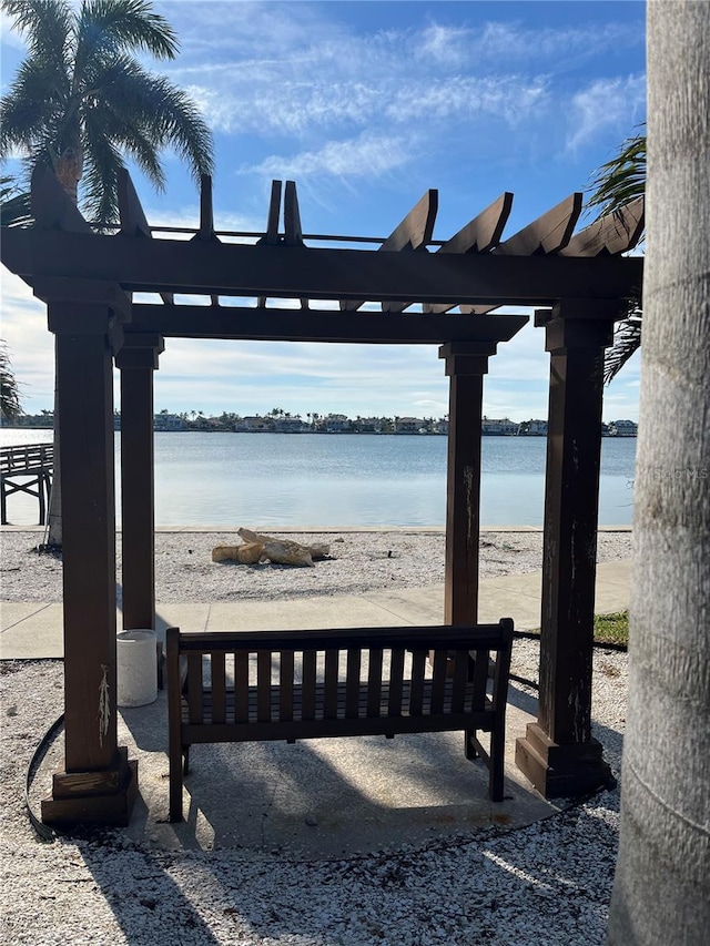 exterior space with a pergola, a water view, and a view of the beach