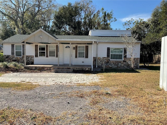 ranch-style home with a front yard, a porch, and solar panels