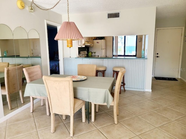 dining space featuring light tile patterned floors and a textured ceiling