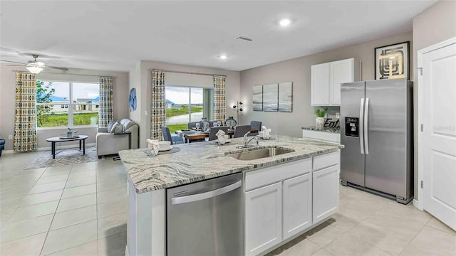 kitchen with a center island with sink, sink, ceiling fan, appliances with stainless steel finishes, and white cabinetry