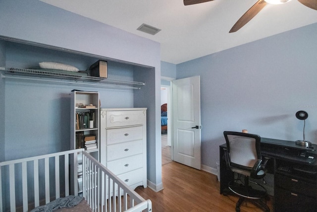 bedroom featuring hardwood / wood-style flooring, ceiling fan, and a nursery area