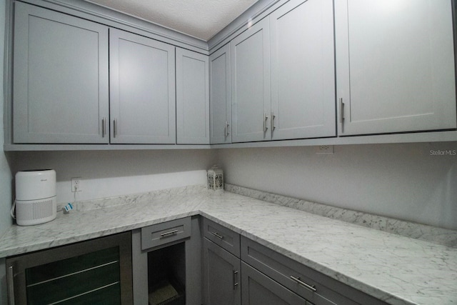 kitchen with gray cabinets, light stone countertops, and beverage cooler