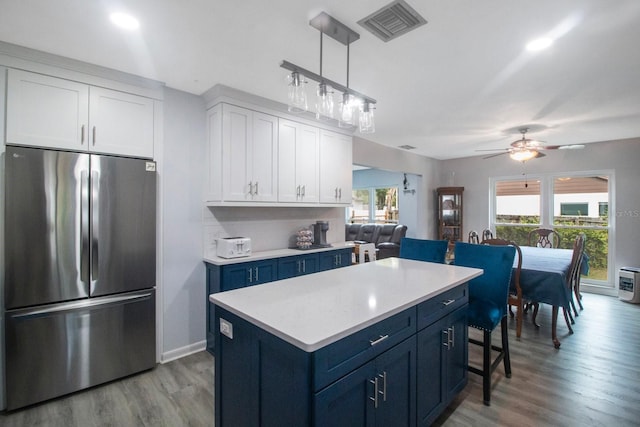 kitchen featuring blue cabinets, stainless steel refrigerator, a kitchen island, ceiling fan, and white cabinets