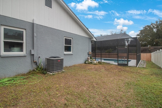 view of yard featuring a fenced in pool, central air condition unit, and glass enclosure