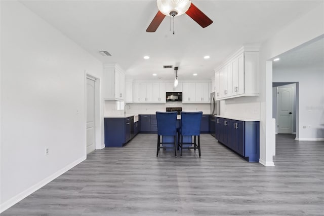 1009 Black Knight Dr, Valrico, FL 33594 - kitchen featuring black microwave, blue cabinets, recessed lighting, ceiling fan, and a center island