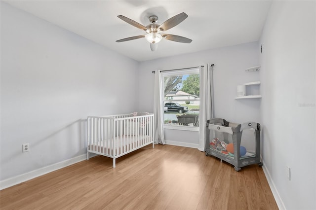 1009 Black Knight Dr, Valrico, FL 33594 - bedroom with light wood finished floors, a crib, and ceiling fan