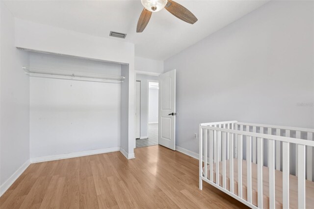 1009 Black Knight Dr, Valrico, FL 33594 - unfurnished bedroom with wood finished floors, a closet, ceiling fan, and a nursery area