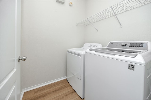 clothes washing area with independent washer and dryer and light hardwood / wood-style flooring