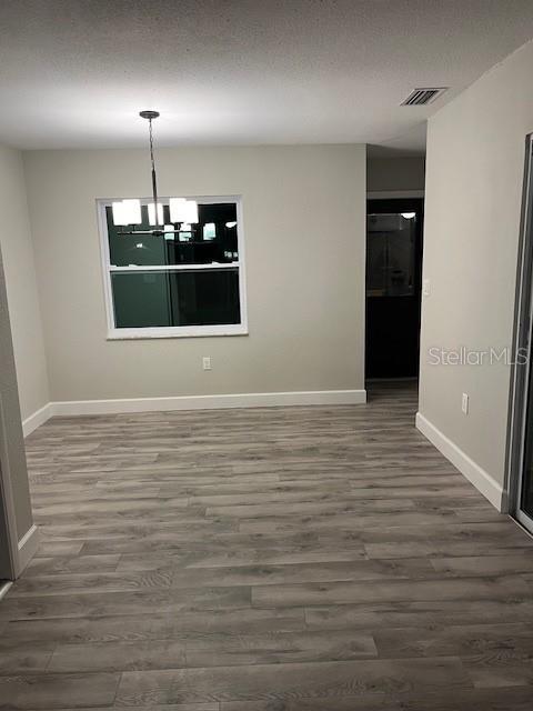 unfurnished dining area featuring an inviting chandelier and dark wood-type flooring