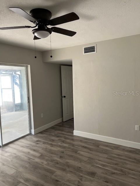 unfurnished room featuring a textured ceiling, ceiling fan, and dark wood-type flooring