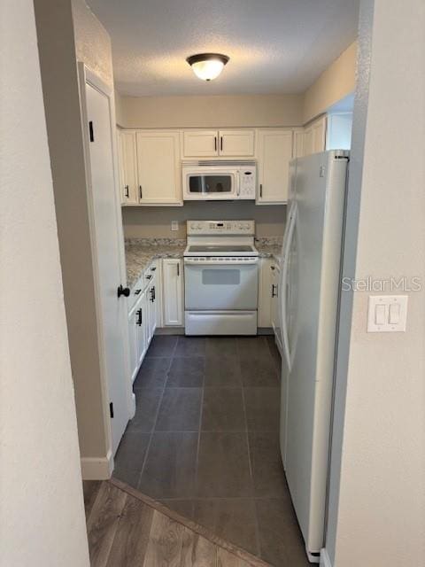 kitchen featuring white cabinetry, light stone counters, and white appliances