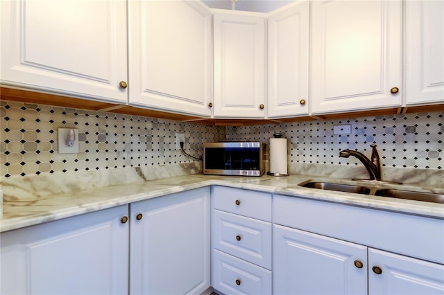 kitchen featuring decorative backsplash, white cabinetry, and sink