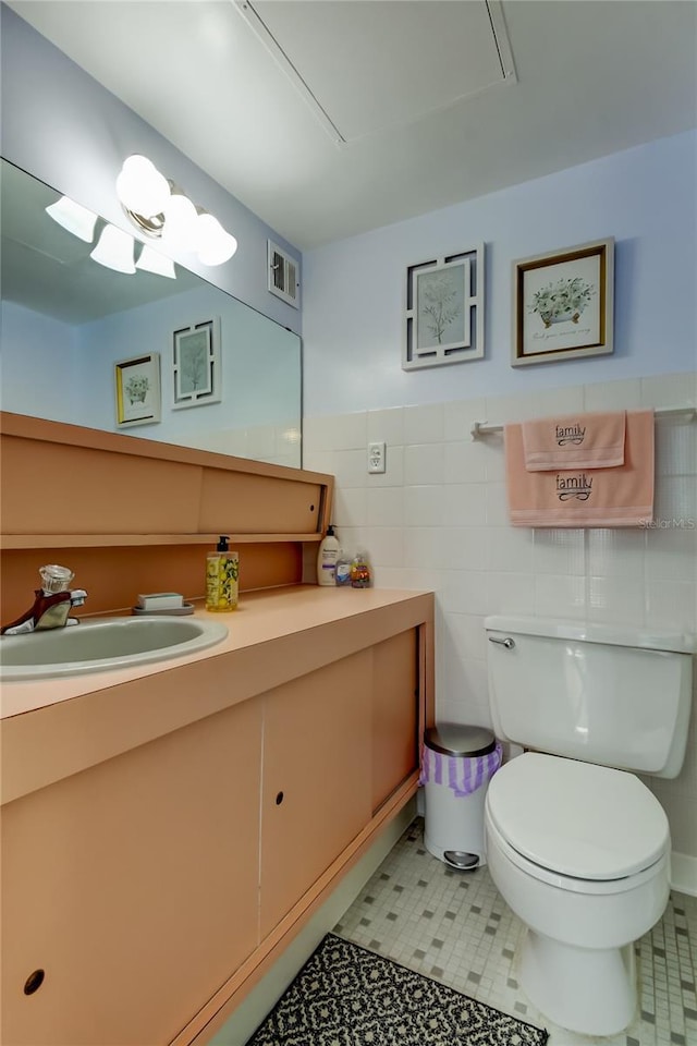 bathroom with vanity, tile walls, and toilet