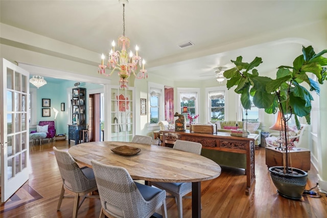 dining area featuring hardwood / wood-style flooring, ceiling fan with notable chandelier, and french doors