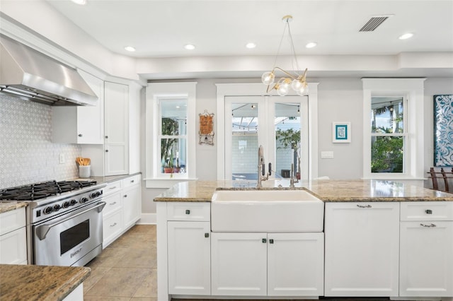 kitchen with light stone counters, sink, high end stainless steel range, and white cabinets