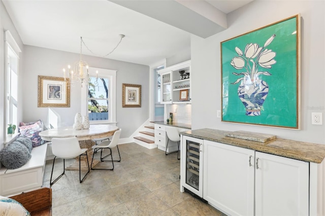 kitchen featuring white cabinetry, decorative light fixtures, beverage cooler, and dark stone countertops