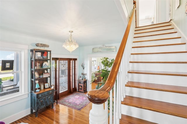 entrance foyer with an inviting chandelier, a healthy amount of sunlight, and hardwood / wood-style floors