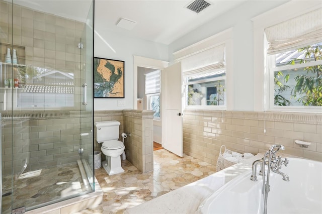 bathroom with tile patterned floors, toilet, independent shower and bath, and tile walls