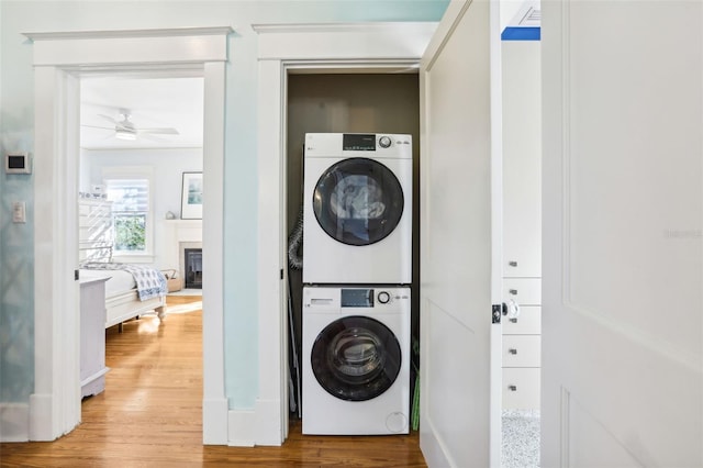 washroom with stacked washer and dryer, hardwood / wood-style flooring, and ceiling fan