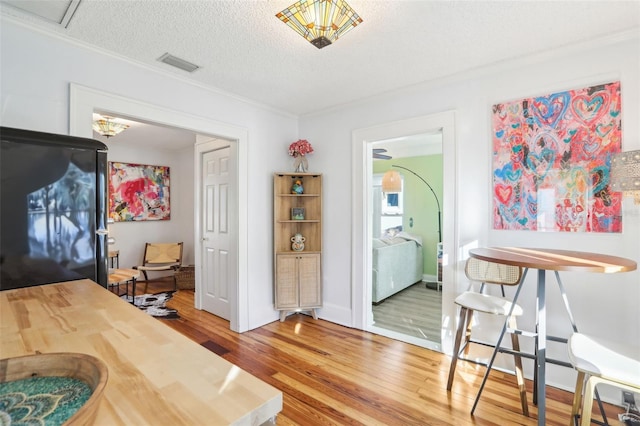 dining area featuring hardwood / wood-style flooring, ornamental molding, and a textured ceiling