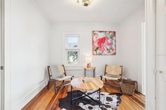 living area with hardwood / wood-style flooring and ornamental molding