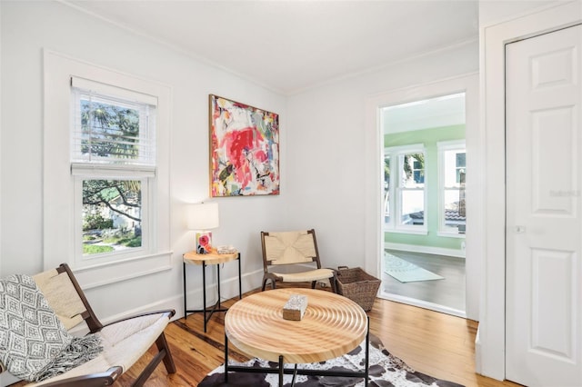 sitting room with hardwood / wood-style flooring and crown molding