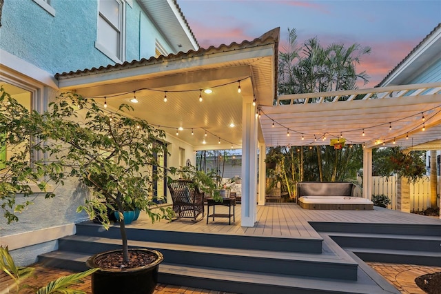 deck at dusk with a hot tub and a pergola