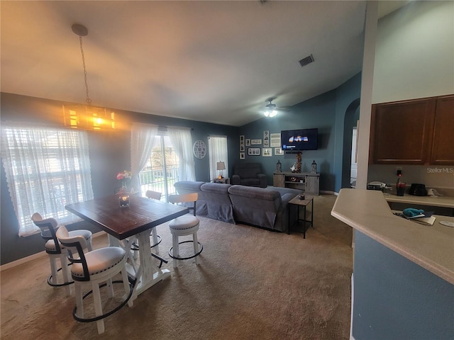 carpeted dining space with ceiling fan and lofted ceiling