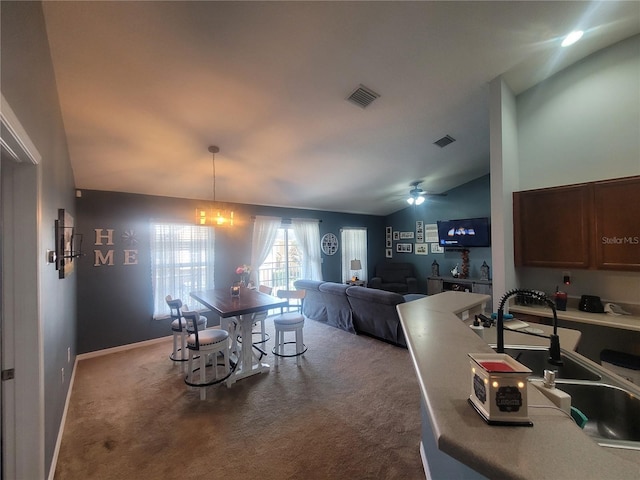 carpeted dining room featuring ceiling fan with notable chandelier, sink, and vaulted ceiling