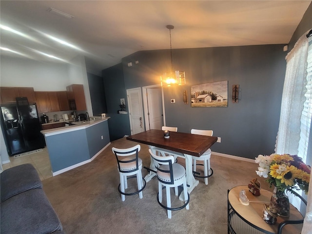 dining room with light colored carpet, lofted ceiling, and an inviting chandelier